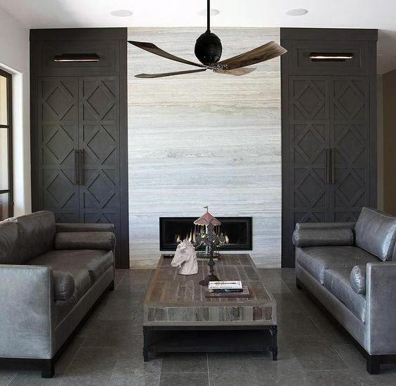 Contemporary living room with dark gray built-in cabinets, minimalist fireplace, leather sofas, and modern ceiling fan