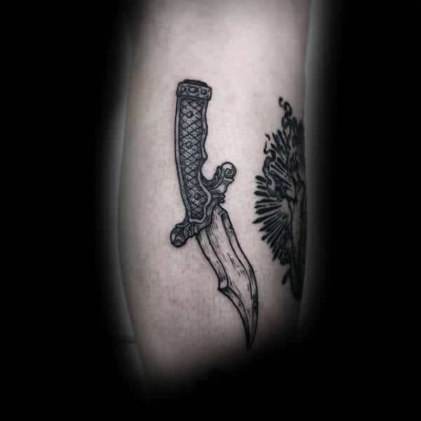A detailed, ornate dagger tattoo on an arm