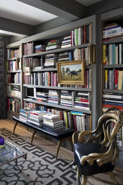 A cozy library with a full bookshelf, ornate chair, and vintage-patterned rug