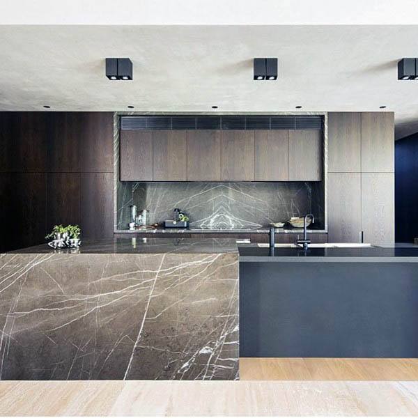 Modern kitchen with dark marble island, matching backsplash, and sleek wood cabinetry.