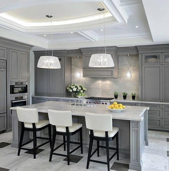 Sophisticated grey kitchen with marble island, white chairs, and sparkling pendant lights.