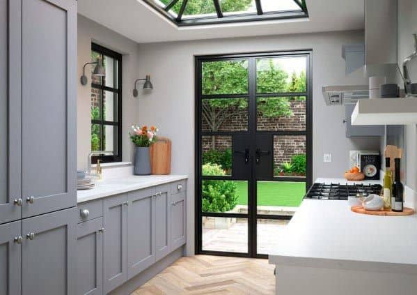 Light grey kitchen with glass doors, skylight ceiling, and view of a lush garden.