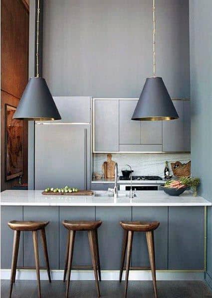 Modern grey kitchen with sleek cabinets, oversized pendant lights, and wooden bar stools.