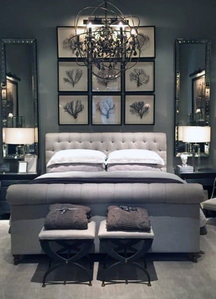 Luxurious bedroom with tufted bed framed botanical art mirrored walls and ornate chandelier.
