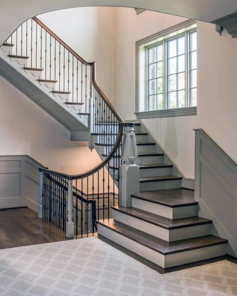 Elegant staircase with dark wooden handrail, bathed in natural light from a large window in a well-lit interior
