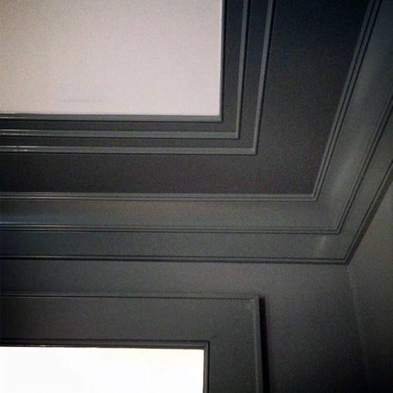 A modern room with sleek, grey-painted crown molding, creating a sharp and contemporary aesthetic around the ceiling and window frame