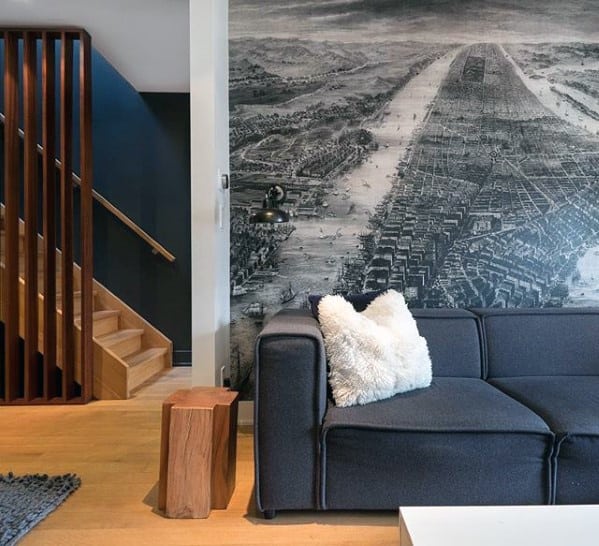 Grey daybed couch in a modern living room with a black and white cityscape mural and wooden accents.