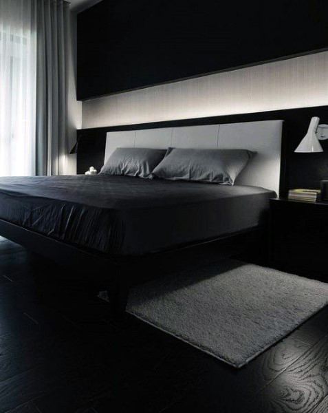Modern bedroom with a dark color scheme, featuring a large bed, grey bedding, and soft lighting
