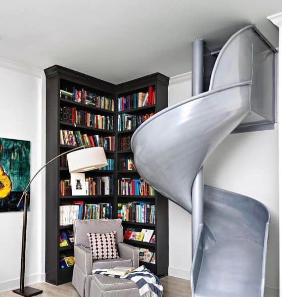 Room with a gray slide, bookshelves, a cozy armchair, and a modern floor lamp