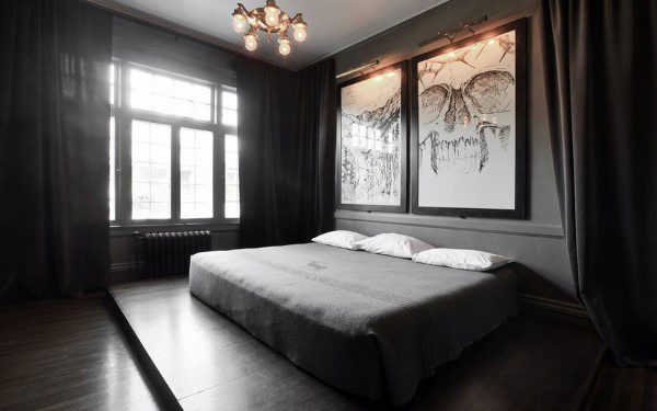 Dark minimalist bedroom with skull wall art, black curtains, and industrial chandelier.