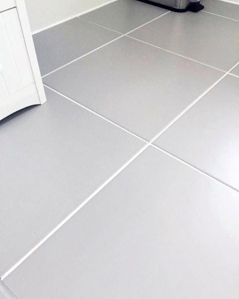 The bathroom floor features large matte gray porcelain tiles paired with clean white grout, creating a simple yet modern look.