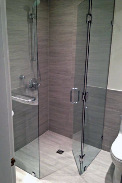 Modern corner shower with glass doors, gray tile walls, and a sleek silver showerhead