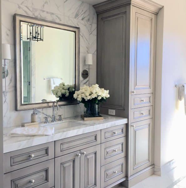 Elegant bathroom with grey cabinets, marble countertop, and large framed mirror.