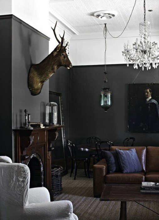 Cozy man cave with a deer mount, chandelier, dark walls, and elegant furniture