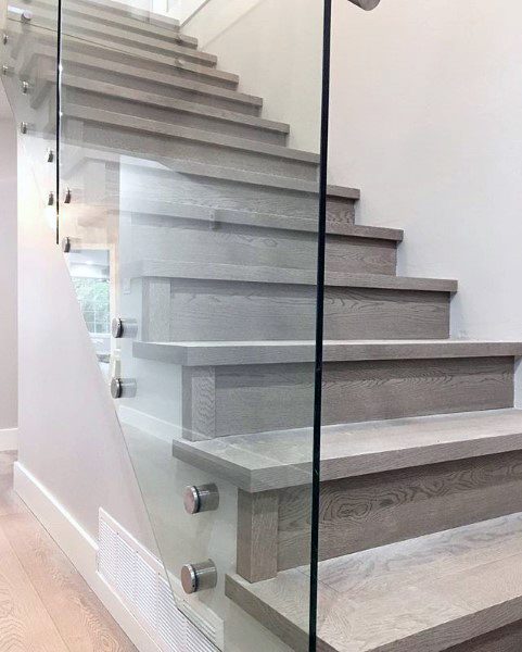 Modern staircase featuring wooden steps, sleek glass railing, and chic metal fixtures