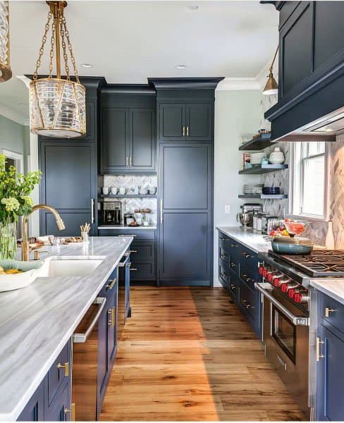 rustic kitchen with blue cabinets wood flooring and marble bench tops 