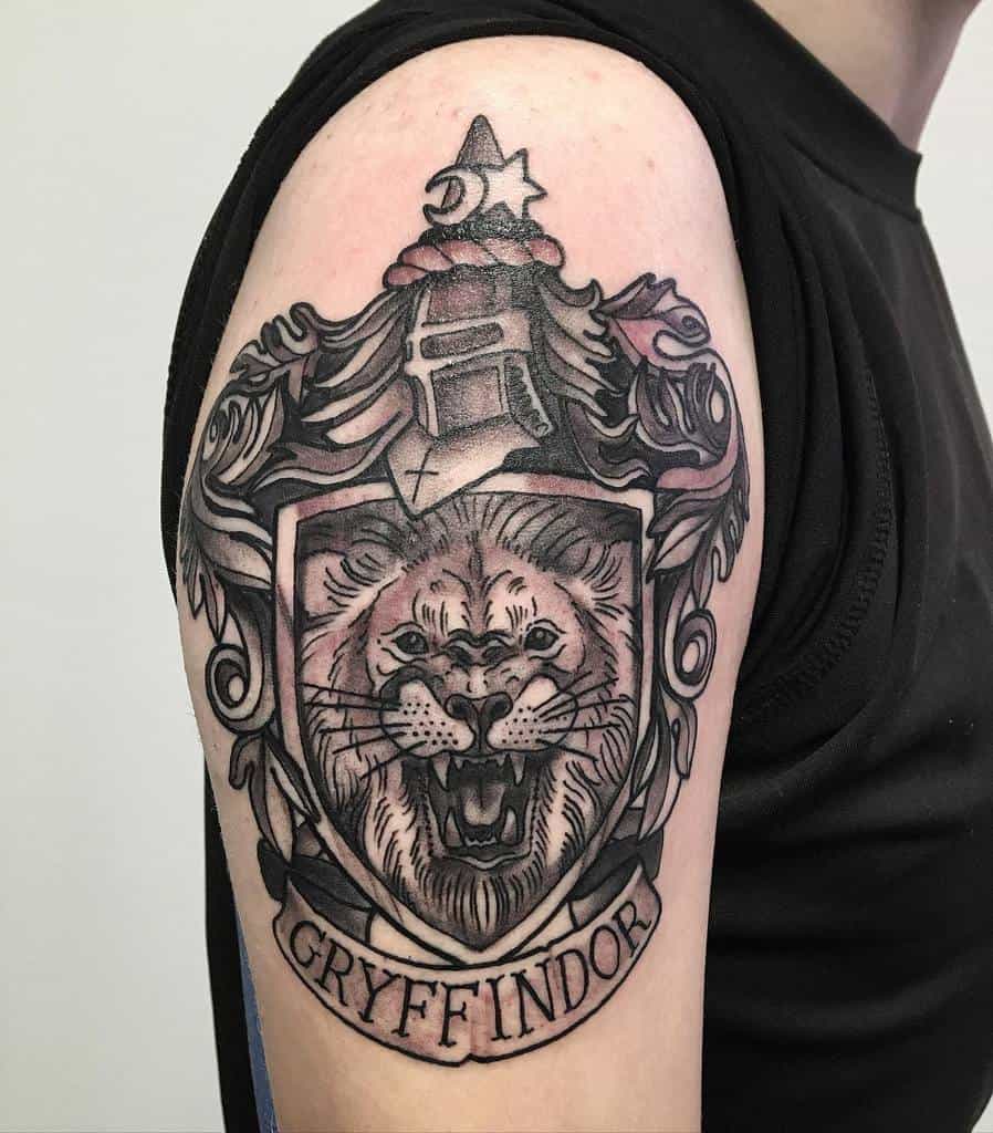 Bold Gryffindor crest tattoo on the upper arm, featuring a fierce lion and medieval armor, symbolizing bravery and courage in Harry Potter