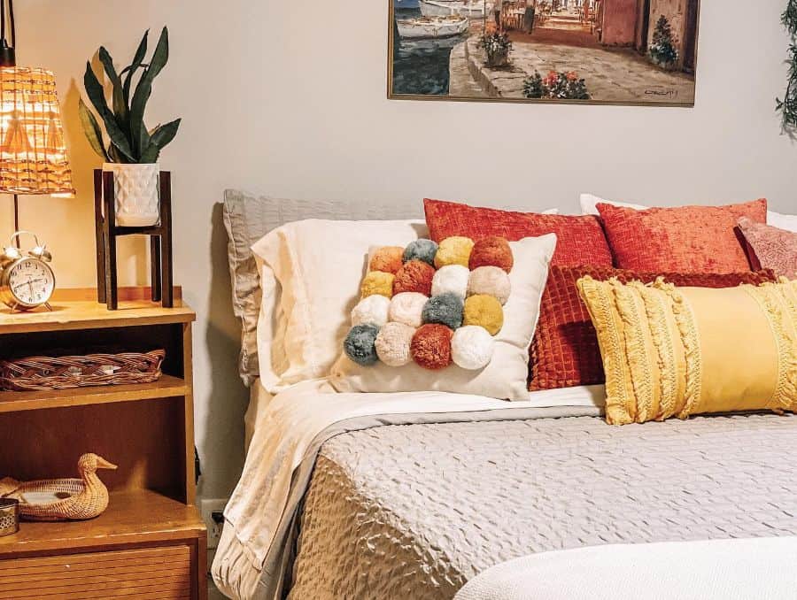 Country-style guest bedroom with colorful throw pillows, warm lighting, and rustic wooden decor.
