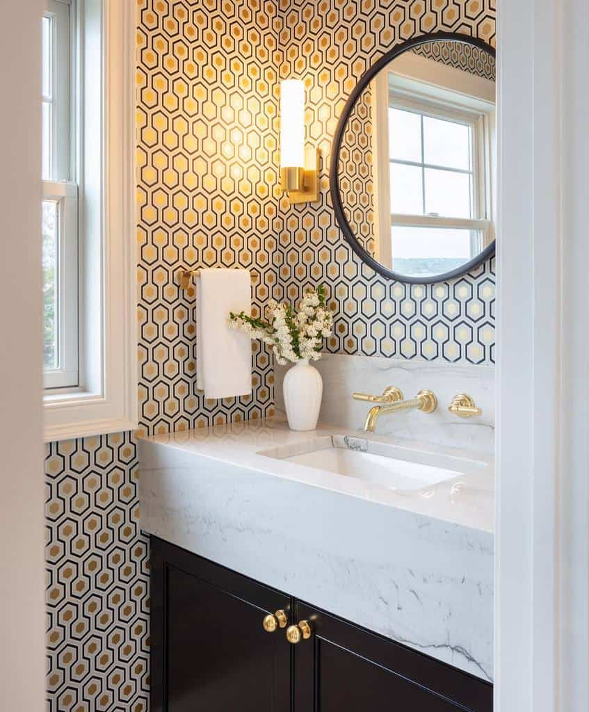 blue and gold hexagonal pattern wallpaper white marble sink gold faucets round wall mirror