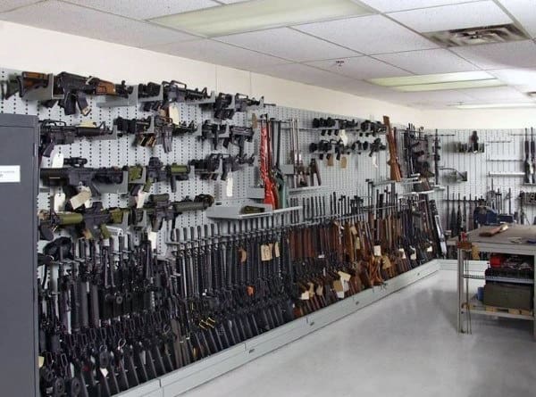 Gun room with extensive wall-mounted firearms and accessories organized on pegboards.