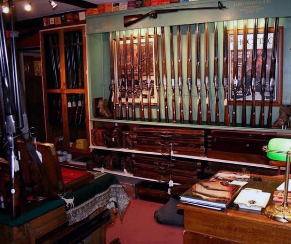 Gun room with wall-mounted rifles, vintage decor, wooden cabinets, and a desk workspace.
