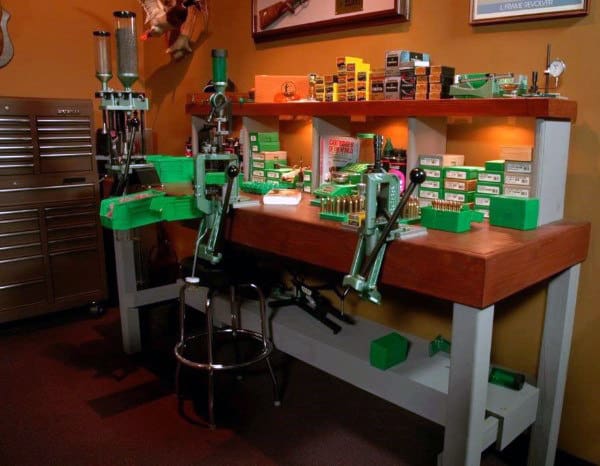 A well-organized reloading bench featuring vibrant green presses, ample lighting, and a dedicated setup for ammo reloading tasks.