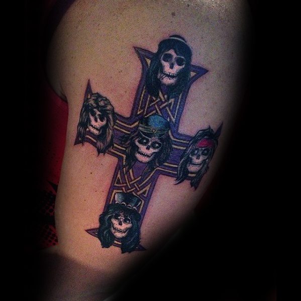 Tattoo of a cross with skulls styled as Guns N' Roses band members, each with unique hair and hats, in dark tones with color accents.
