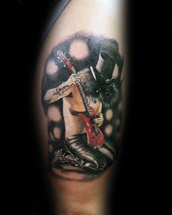 Realistic tattoo of Slash kneeling shirtless while playing a red guitar, wearing his iconic top hat, set against a glowing stage-like backdrop.