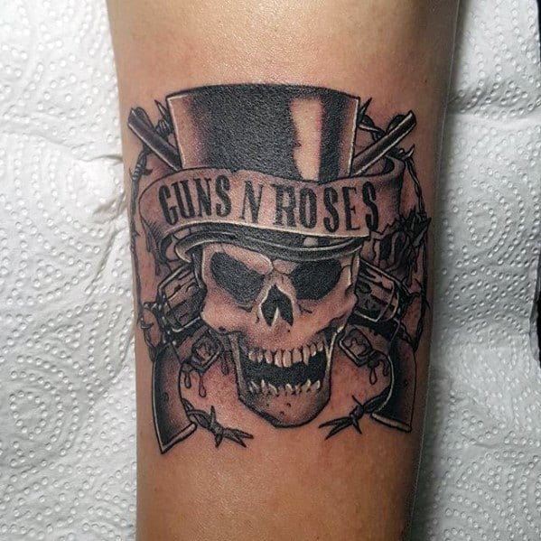 Skull tattoo with top hat labeled "Guns N' Roses", flanked by pistols and barbed wire for a gritty rock-inspired look.