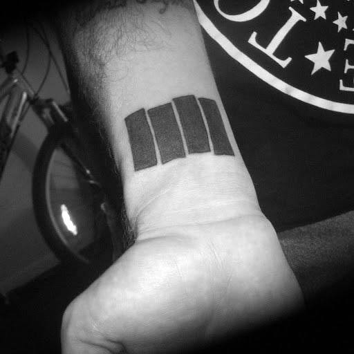 Bold Black Flag bars tattoo on the inner wrist, angled upward to reflect defiance and iconic punk simplicity.