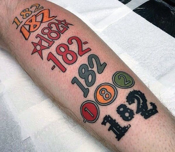 Tattoo featuring various stylized representations of "182," with different colors and designs, creating a dynamic, graphic sequence along the forearm.