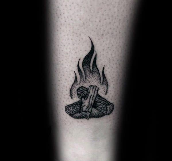 Minimalist blackwork campfire tattoo with shaded flames and detailed wood logs, placed on the forearm.