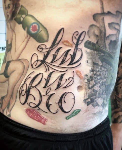 Large script tattoo on the stomach with realistic gummy candies incorporated into the design, blending bold lettering with playful candy details.