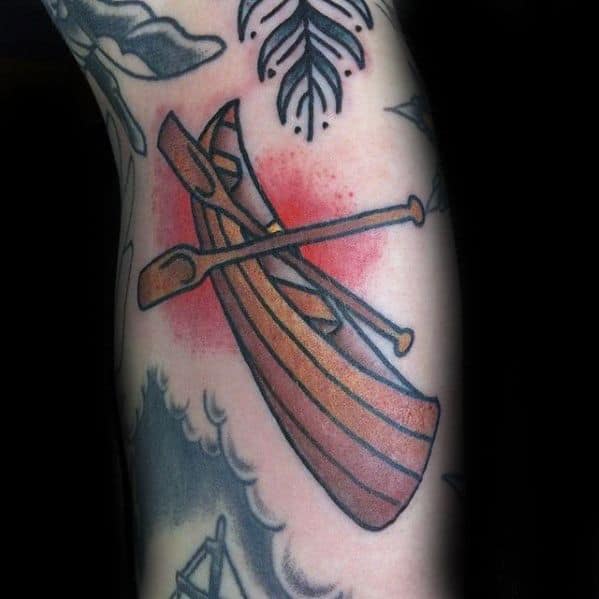Alt text: Bold tattoo of a canoe with oars, highlighted with red shading in the background, adding a striking visual effect.