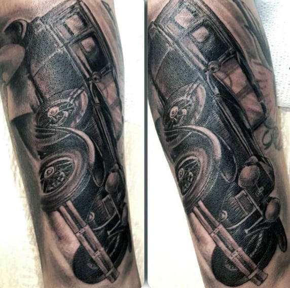 Close-up of a realistic black and grey tattoo of a vintage car on an arm