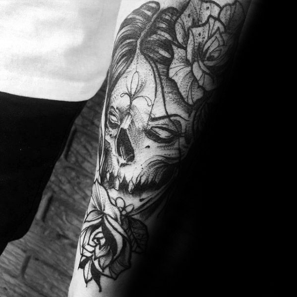 La Catrina tattoo in a sketch style showing a skeletal face with floral details, surrounded by blooming roses.