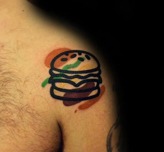 Cheeseburger tattoo with abstract color accents graces a person's shoulder