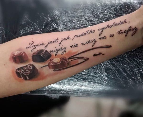 Realistic tattoo featuring assorted chocolates with a drizzle of syrup and a Polish quote translating to "Life is like a box of chocolates."