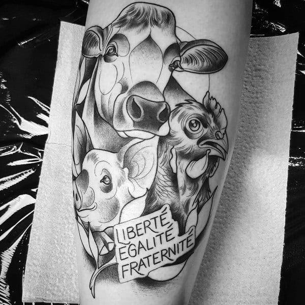 Black and grey tattoo featuring a cow, pig, and chicken with a banner reading “Liberté Égalité Fraternité” in a unity-themed design.