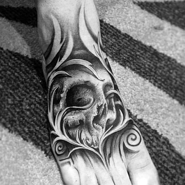 Tattoo of a detailed skull with swirling patterns, covering the top of a foot