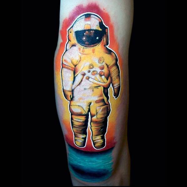 Bold Deja Entendu astronaut tattoo with thick white outline, fiery sunset background, and deep teal ocean at the bottom.