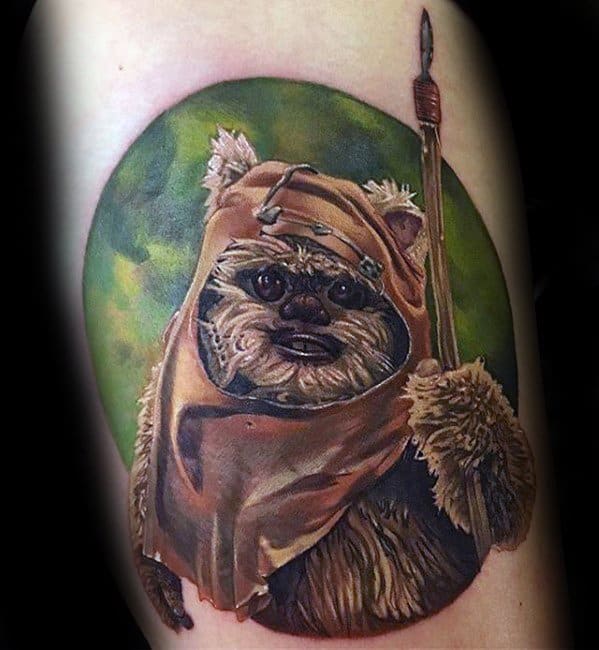 Hyper-realistic Ewok tattoo with a detailed tan hood, fur texture, and spear, set against a soft green circular background.