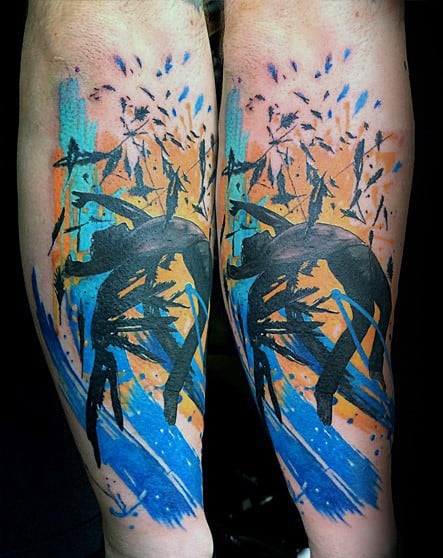 Vibrant abstract tattoo of a falling figure with bold splashes of blue, orange, and black ink, symbolizing chaos and movement.