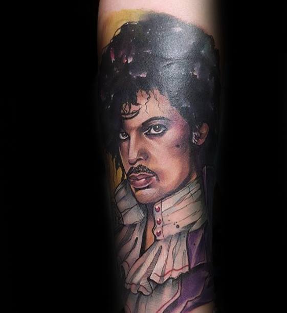 Tattoo of a Prince-like figure with curly hair and a ruffled shirt on a forearm against a black background