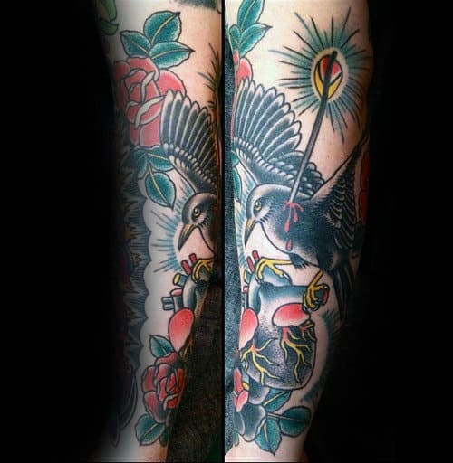 Guy With Forearm Tattoo Of Black Crow Flying With Heart Traditional Design