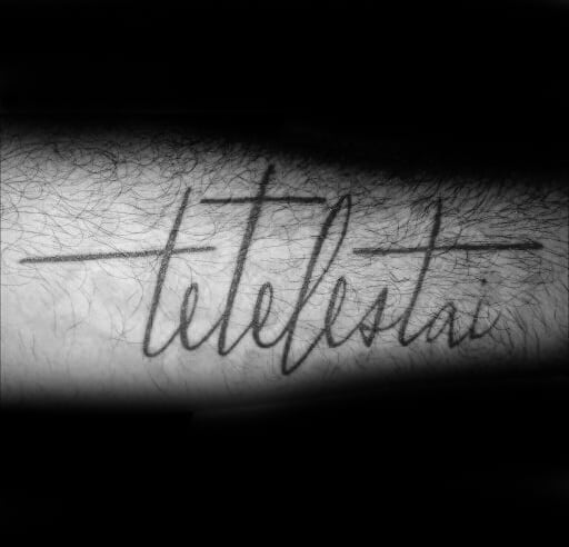 Guy With Forearm Tattoo Of Script Tetelestai Word