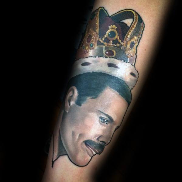 Realistic portrait tattoo of Freddie Mercury wearing a royal crown, highlighting his legacy as the king of rock with detailed shading and color.
