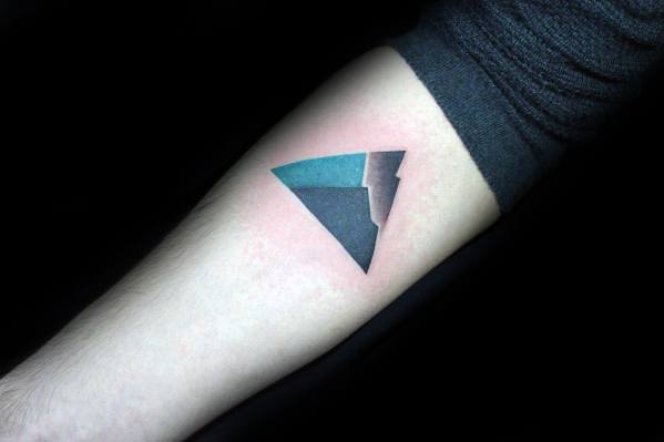 Modern minimalist mountain tattoo in a triangle shape with bold black and teal gradient shading on the inner forearm.