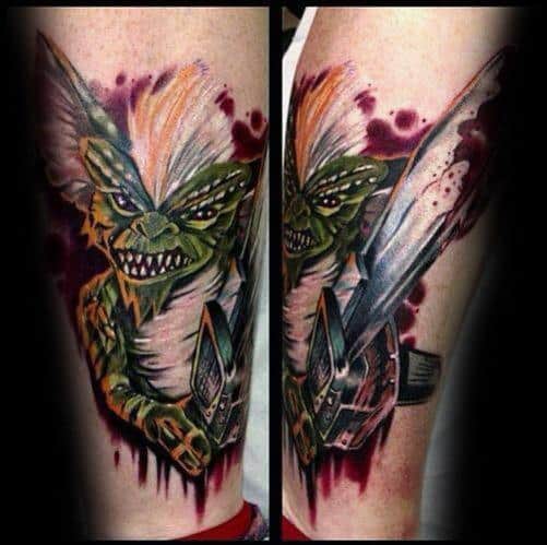 Intense Gremlin tattoo with sharp teeth, white hair, and a bloodied chainsaw, blending horror elements with bold colors and shading.