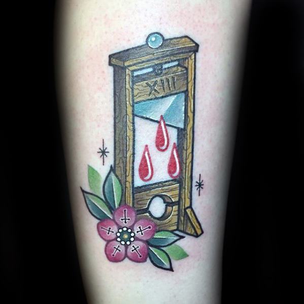 Colorful neo-traditional guillotine tattoo with red blood drops, Roman numeral XIII, and a pink flower with leaves at the base.